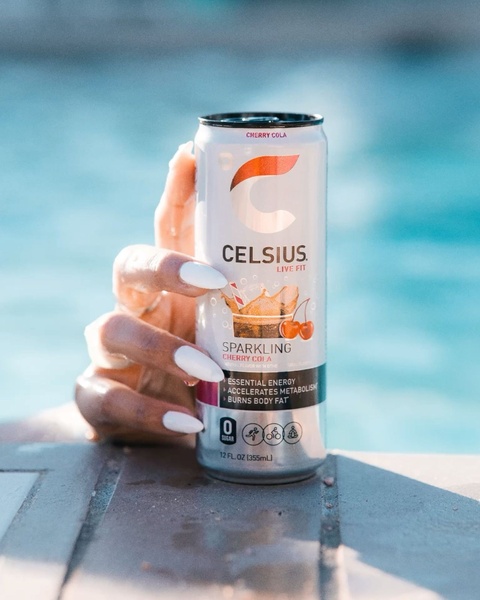A close-up product shot of an energy drink held against a bright blue pool background, emphasizing a clean, active, and refreshing lifestyle aesthetic.
